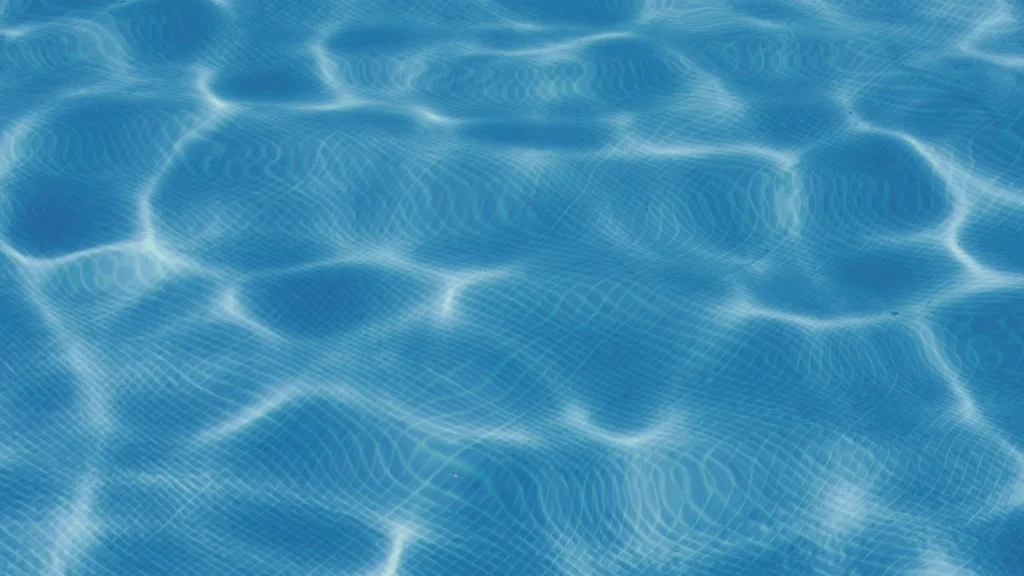 Superfície de água azul e cristalina de piscina com azulejos ao fundo